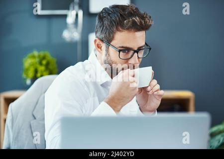 Taking a tea break. Shot of a young businessman drinking a cup of tea while working in an office. Stock Photo
