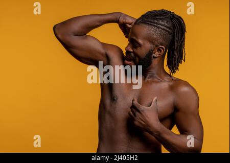 Handsome strong young African American male athlete with dreadlocks flexing his biceps before the camera Stock Photo