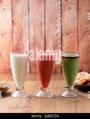 Freshly blended fruit smoothies of various colors and tastes in tall Glass. White, Red, Green. On Wooden Table Stock Photo