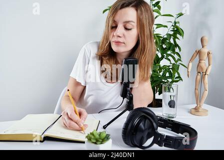 Woman sitting at table and writing notes in notebook, Online courses, Studying at home Stock Photo