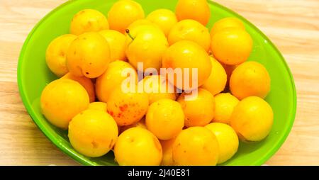 sprinkled yellow cherry plum, in bowl on table Stock Photo