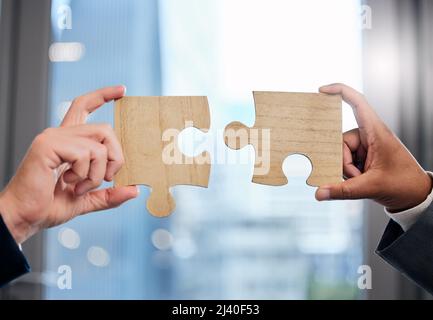 Inaction breeds doubt and fear, stop thinking, get busy. Cropped shot of two businesspeople completing a puzzle together in a modern office. Stock Photo