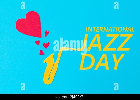 A cutted out of felt saxophone from which hearts flew out, on a blue background. Flat lay. International Jazz Day. Stock Photo