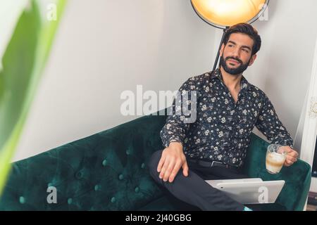 Young handsome man looking thoughtfully into the distance with a hot cup of coffee with his laptop. High quality photo Stock Photo