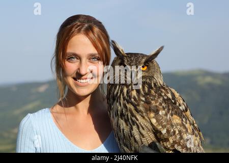 Front view portrait of a happy falconer with an eagle owl looking at camera Stock Photo
