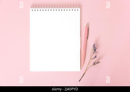 Notepad with white blank sheets, pink pen and dried flower sprig Stock Photo