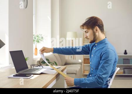Serious young man reading business letter or some documents he got by paper mail Stock Photo