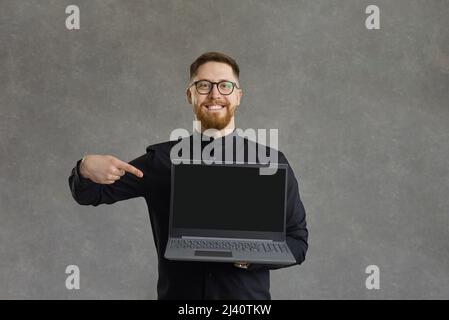 Studio portrait of happy young man pointing at blank screen of his laptop computer Stock Photo