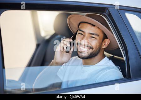 The open road is a beckoning. Shot of a young man sitting in a car while using his phone. Stock Photo