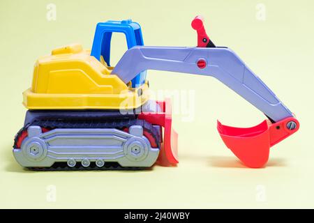 Plastic excavator car on yellow background. Construction machinery car for digging for toy store and children. Stock Photo