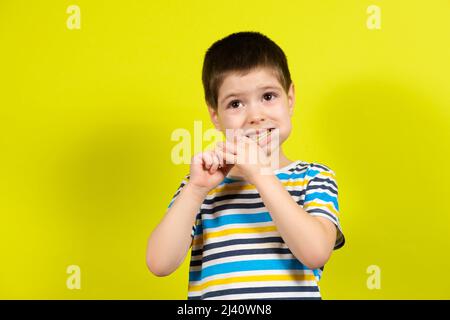 A little boy brushes his teeth with a toothbrush on a yellow background with place for text. Stock Photo