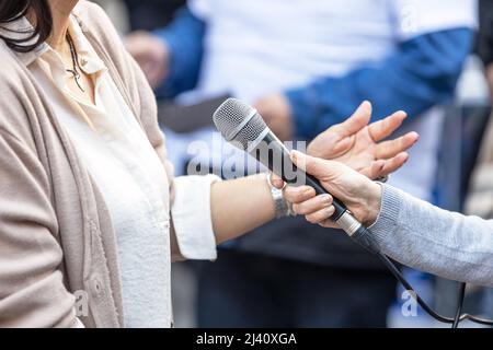 Reporter holding microphone making media interview with female politician or business woman Stock Photo