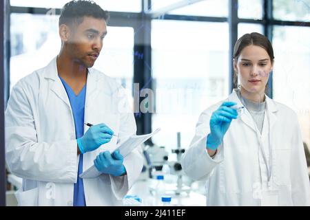 Doing the maths to prove their theory. Shot of two scientists solving equations on a glass screen in a laboratory. Stock Photo