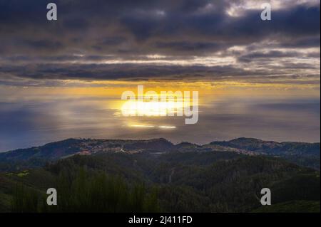 Sunset over Atlantic Ocean with coastal villages in Madeira, Portugal Stock Photo