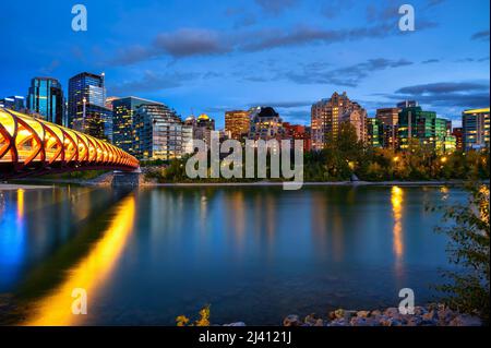 Peace Bridge across the Bow River and Calgary skyline photographed at night Stock Photo