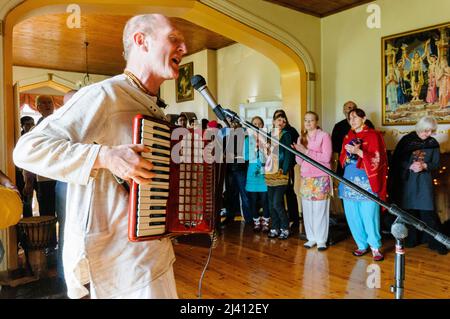 28th February 2010.  Inis Rath, Fermanagh, Northern Ireland.  A Hare Krishna devotee wearing a faded robe plays an accordian during a temple ceremony Stock Photo