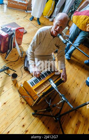 28th February 2010.  Inis Rath, Fermanagh, Northern Ireland.  A Hare Krishna devotee wearing a faded robe plays a squeezebox during a temple ceremony Stock Photo