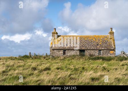 An old stone croft house with a lichen covered roof on the island of Sanday, part of the Orkney Isles in Scotland. Stock Photo