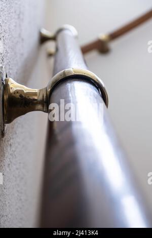 Oak banister with shiny copper banister holder. Focus on the leading edge of the brass ring. Blurred banister in the background Stock Photo