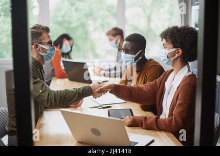 business people in protective masks shaking hands. Stock Photo