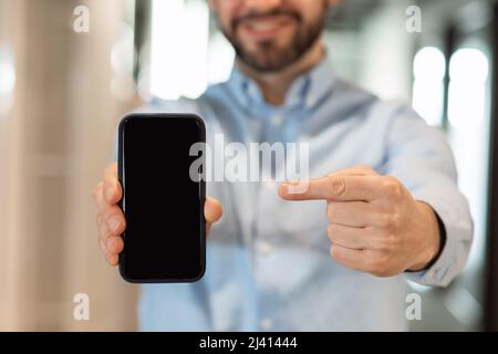 Businessman pointing at black empty smartphone screen Stock Photo