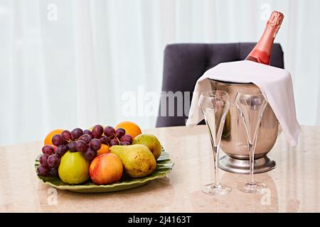 Champagne in a Hotel Room, Ice Bucket, Glasses and Fruits on a Plate - Honeymoon Concept Stock Photo