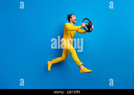 Full length body size view of attractive guy jumping holding steering wheel isolated over bright blue color background Stock Photo