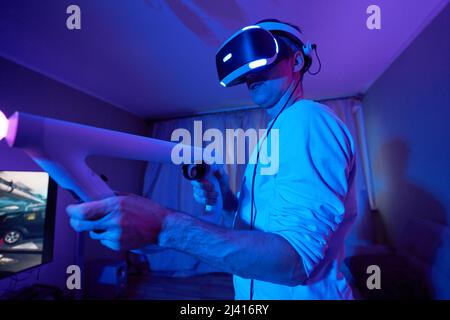 Man with virtual reality headset and joystic is playing game Concept of virtual reality, games, entertainment and communication. Stock Photo