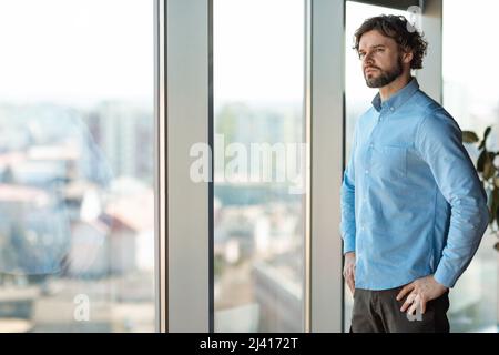 Portrait of confident business man looking through window Stock Photo