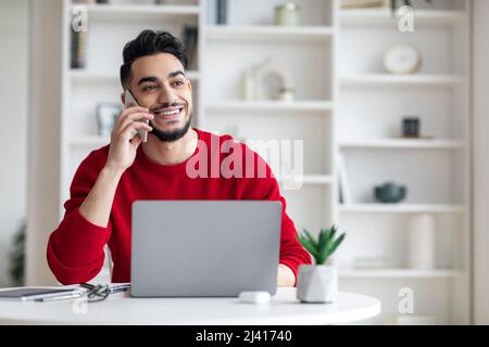 Handsome Young Middle Eastern Male Talking On Mobile Phone At Home Office Stock Photo