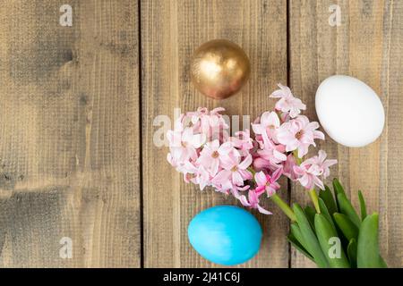 blue, white and golden eggs and pink hyacinth flowers on wooden table. Happy Easter concept. Easter background Top view Stock Photo