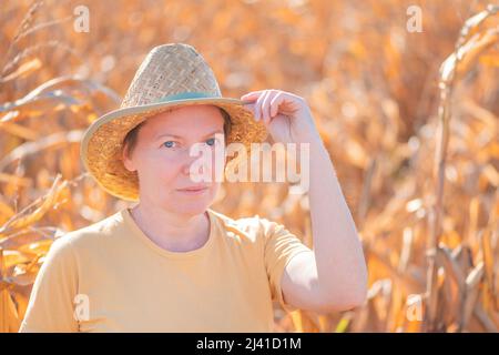 Female agronomist and farmer standing in ripe harvest ready dent corn field and looking over plantation Stock Photo