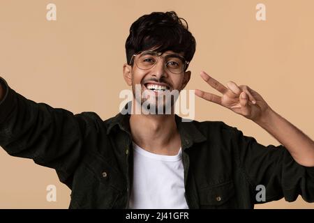 Cheerful middle eastern man taking selfie, gesturing Stock Photo