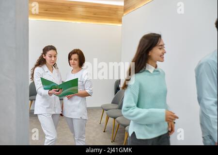 Two nurses discussing medical document in corridor Stock Photo