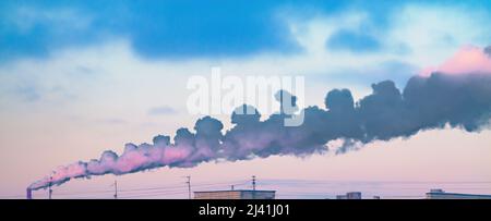 Dark smoke spreads horizontally from pipe on the background of blue-pink sunrise sky. Illustrative material of ecology problems and air pollution Stock Photo