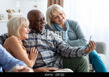 Multiracial group of pensioners using mobile phone Stock Photo