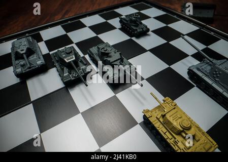 Toy tanks with chess on chessboard. Concept of military strategy., Stock  image