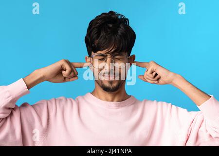 Annoyed young india guy covering his ears Stock Photo