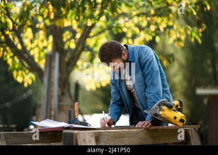 Handyman measuring a board, outside in garden. Stock Photo