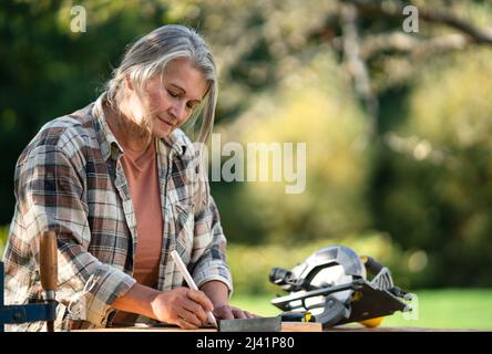 Handy female carpenter working in carpentry diy workshop outdoors Stock Photo