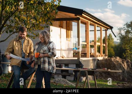 Mature couple having coffee break when working together on construction site of their new house. Stock Photo