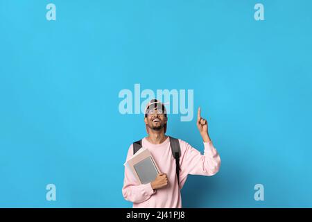 Positive indian guy student pointing up at copy space Stock Photo