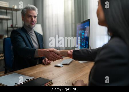 Financial advisor shaking hand with his client indoors in office. Stock Photo