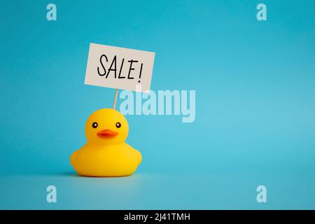 Rubber duck carries a signboard with the word sale. Price discount and promotion offer in shopping business. Stock Photo