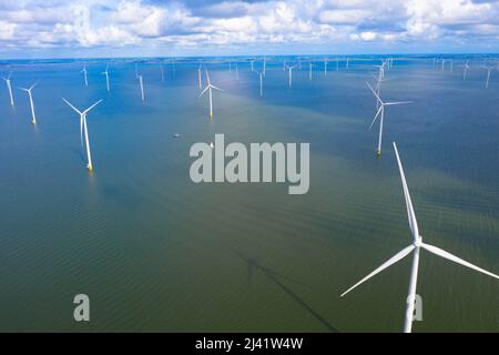 Aerial view of enormous windmills stand in the sea along a dutch sea. Fryslân wind farm, the largest inland wind farm in the world. Afsluitdiijk