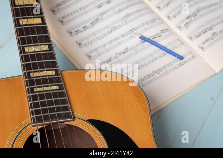 Music recording scene with guitar, music sheets and pencil on wooden table, closeup Stock Photo