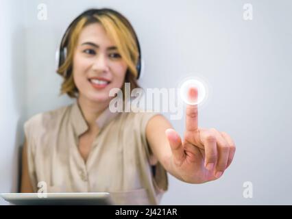 Close-up touching point on virtual screen touched by Asian woman finger while using tablet and headphone on white background with copy space. Music cr Stock Photo