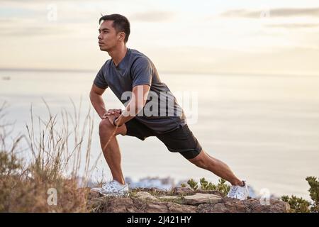 Spending time in nature can be therapeutic. Shot of a young man exercising in nature. Stock Photo