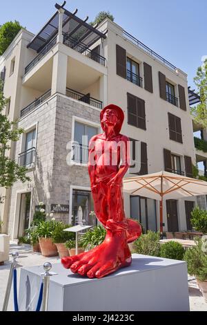 TIVAT, MONTENEGRO - JULY 29, 2021: Red sculpture of a man with big legs in city, modern art installation Stock Photo