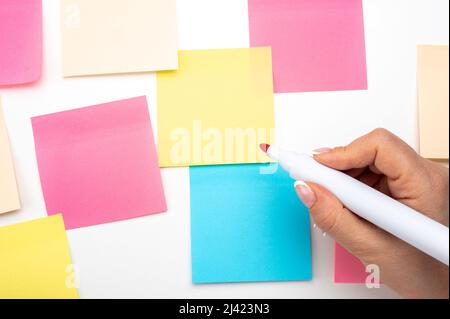 Hand written notes red marker sticker notes paper. hand with red marker ready to write. Many colored empty sticker notes on wall. Business people meet Stock Photo